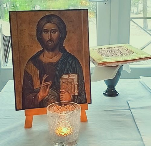 Kristus-ikoni, jonka edessä tuikkukynttilä. Taustalla ehtoollisvälineet.