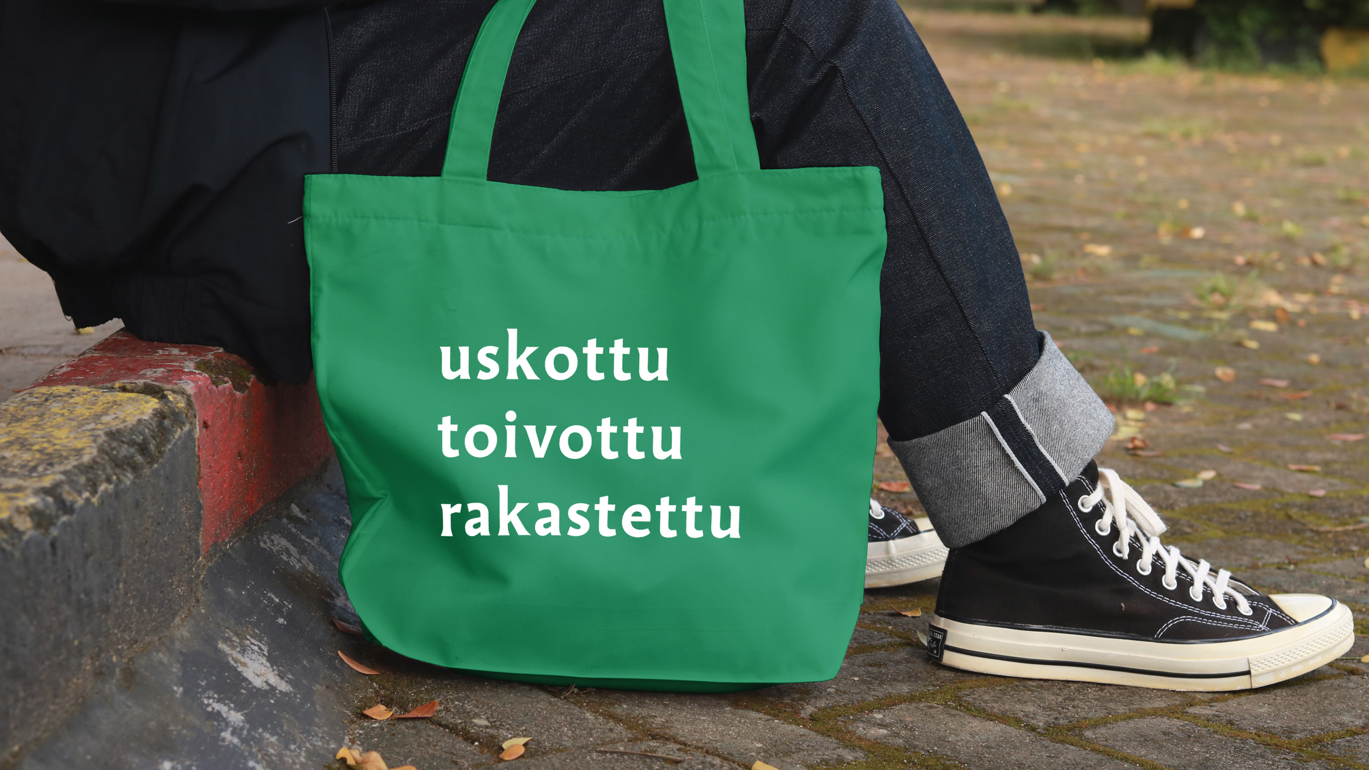 Kuvassa näkyy portailla istuvan henkilön jalat ja maassa vihreä kangaskassi jossa on seurakuntavaalien kamp...